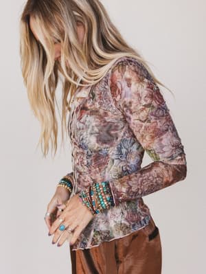 Person wearing a floral long-sleeve top with a neutral background