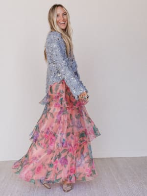 Woman wearing a floral dress with a sequined top against a plain background