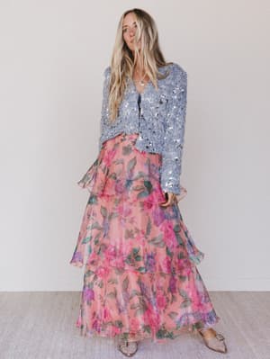 Woman wearing a sequin top and floral skirt against a white background