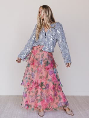 Woman wearing a sequin top and floral skirt on a plain background