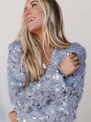 Woman wearing a blue sequin dress against a plain background