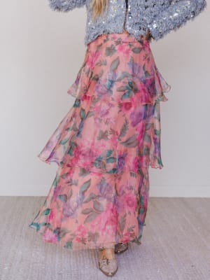 Person wearing a floral skirt and sequin top on a plain background