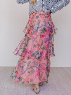 Person wearing a floral skirt and sequin top on a plain background