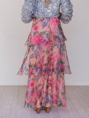 Person wearing a floral tiered skirt and sequin top against a plain background