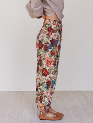 Person wearing floral pants with a plain background