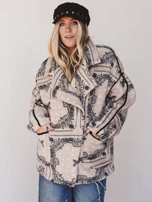 Person wearing a patterned jacket and cap against a plain background