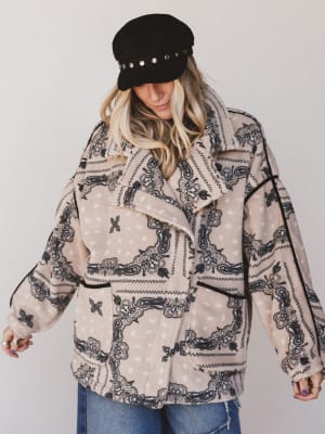 Person wearing a patterned jacket and black cap against a plain background