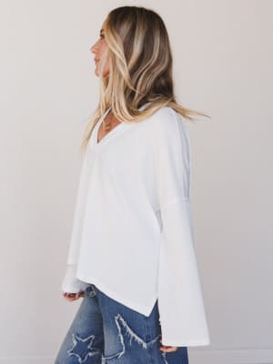 Woman wearing a white blouse and blue jeans against a plain background