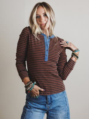 Woman wearing a striped shirt and jeans with a neutral background
