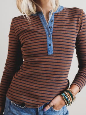 Person wearing a brown and blue striped long-sleeve shirt with denim collar.