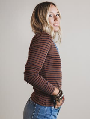 Woman wearing a brown and blue striped long-sleeve top against a plain background