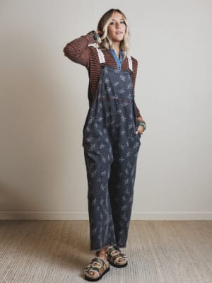 Woman wearing a patterned denim jumpsuit with a plain background