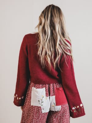 Person wearing a red cardigan with patterned red pants with floral details.