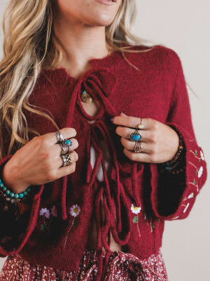Close-up of a person wearing a red embroidered sweater with floral patterns.