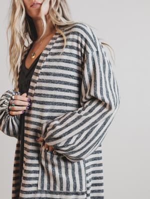 Person wearing a striped cardigan with a plain background