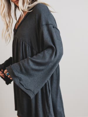 Person wearing a dark gray cardigan with a plain background