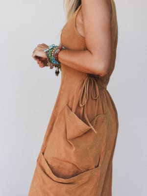 Brown dress worn by a person with colorful bracelets on a plain background