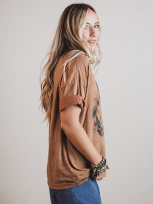 Woman wearing a brown shirt with a tattoo on a plain background
