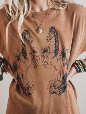 Brown t-shirt with horse and floral designs worn by a person.