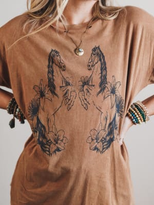 Brown t-shirt with horse and floral designs worn by a person.