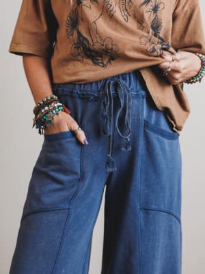 Person wearing a brown floral top and blue pants with a neutral background