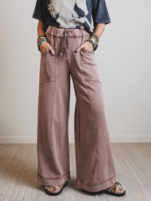Person wearing wide-leg brown pants with a plain background
