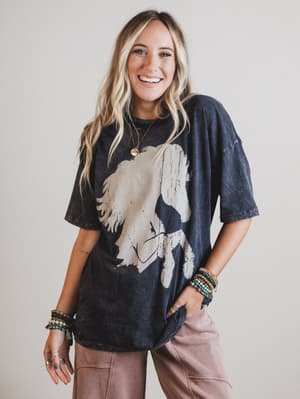 Woman wearing a charcoal gray t-shirt with a graphic design, standing against a plain background