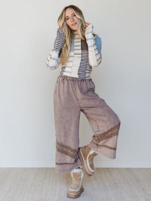 Woman wearing a striped sweater and brown pants with a white background