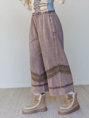 Woman wearing wide-leg brown pants with decorative crochet trim and light brown platform boots.