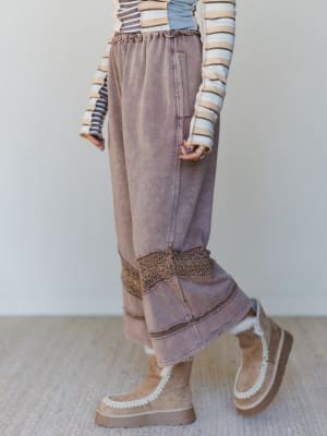 Woman wearing wide-leg brown pants with crochet trim and brown platform boots.