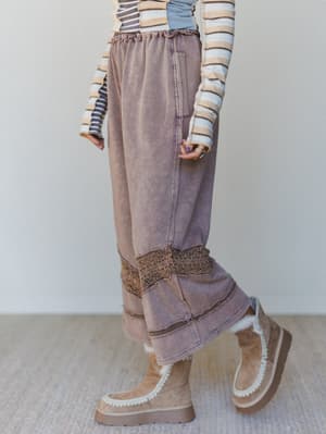 Woman wearing wide-leg brown pants with crochet trim and brown platform boots.