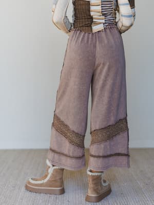 Back view of a woman wearing wide-leg brown pants with decorative trim and brown platform boots