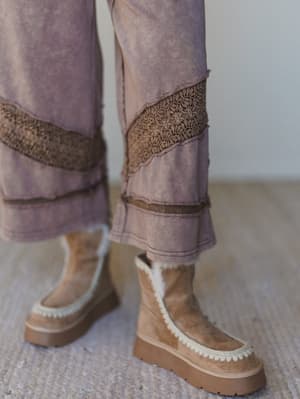 woman wearing wide-leg brown pants with decorative trim and brown platform boots