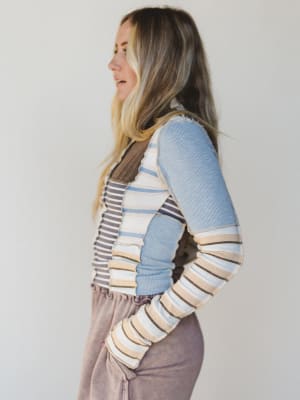 Woman wearing a striped patchwork sweater against a plain background