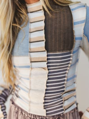 Close-up of a woman wearing a striped sweater with a patchwork pattern.