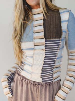 Person wearing a colorful striped sweater with a neutral background