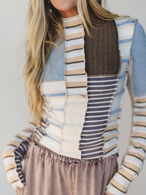 Person wearing a colorful striped sweater with a neutral background