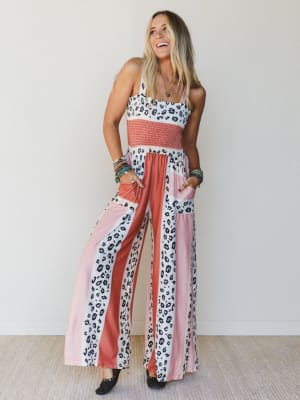 Woman wearing a colorful jumpsuit with leopard print and pink accents against a plain background