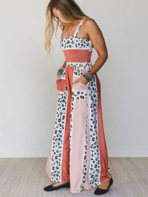 Woman wearing a long, patterned dress with a mix of colors on a plain background