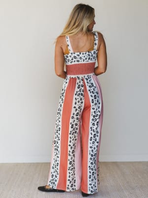 Woman wearing a leopard print and pink jumpsuit against a white background