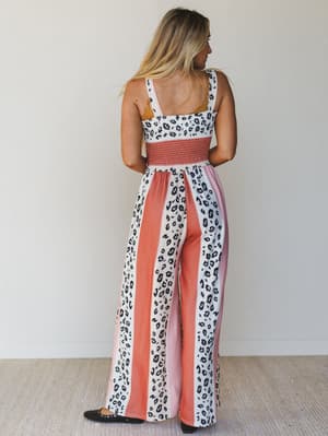 Back view of woman wearing a leopard print and pink jumpsuit against a white background