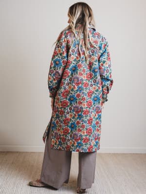 Person wearing a colorful floral coat in a minimal indoor setting