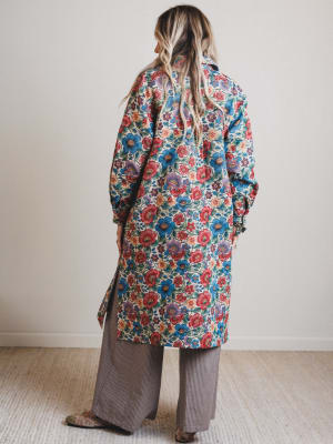 Person wearing a colorful floral coat in a minimal indoor setting