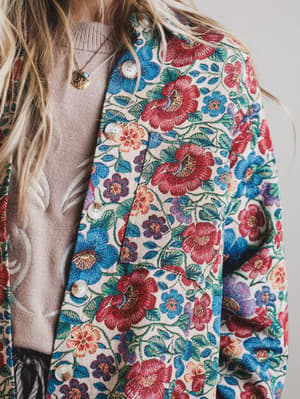 Close-up of a colorful floral-patterned jacket with a neutral sweater underneath.