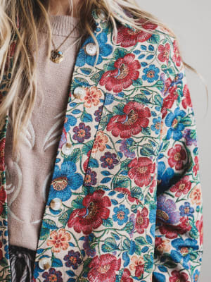 Close-up of a colorful floral-patterned jacket with a neutral sweater underneath.