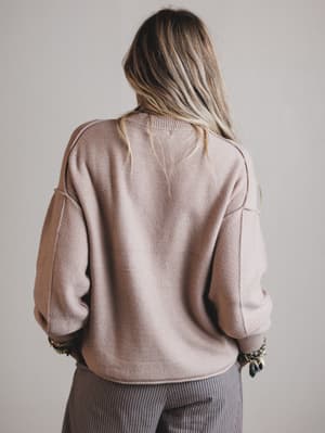 Person wearing a beige sweater with a neutral background