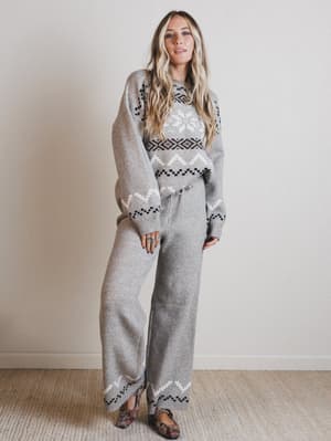 Woman wearing a gray patterned outfit against a plain background