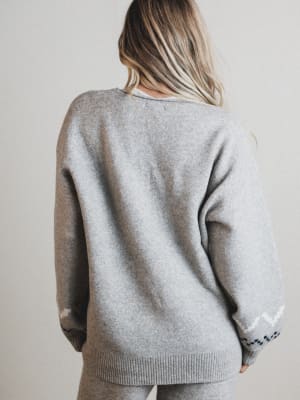 Person wearing a gray sweater with a plain background