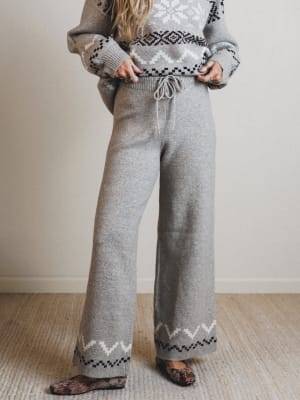 Person wearing a gray knit outfit with patterned details on a neutral background