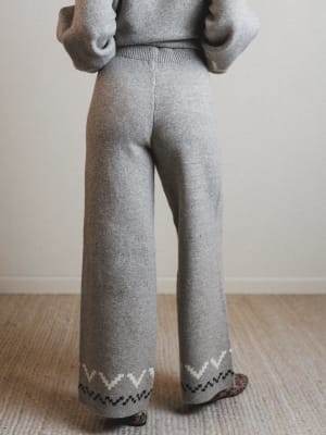 Person wearing gray knit pants with a subtle pattern on a neutral background